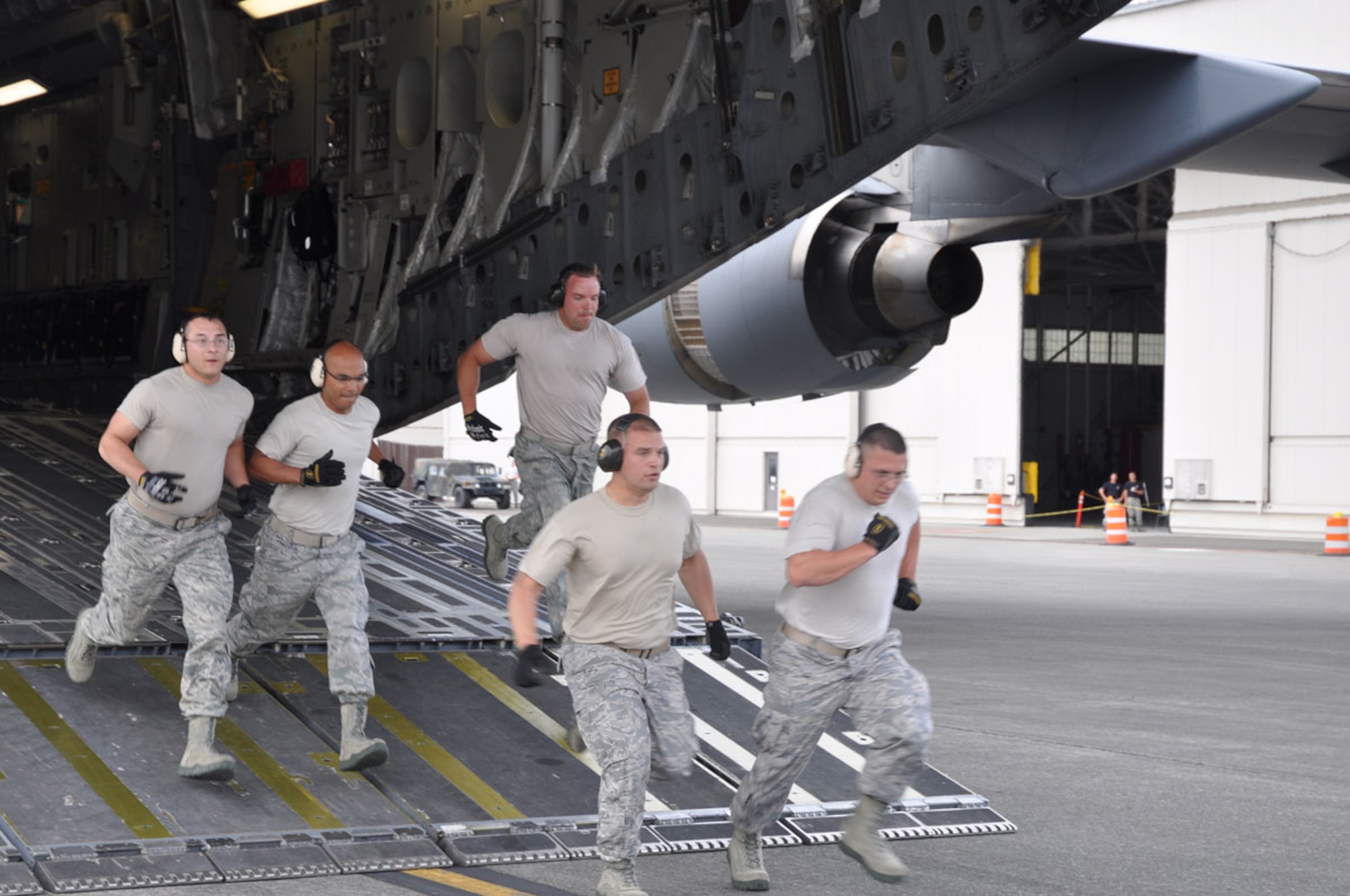 Left to right: Staff Sgt Cody Phillips, Tech. Sgt Michael Gogue, Staff Sgt. Michael Cochran, Staff Sgt. John McGuire and Staff Sgt. Chris Boles runoff the Team Alaska 517th Airlift Squadron C-17 during the Engine Running Offload Event at the 2011 AMC Rodeo on 27 July. (U.S. Air Force photo/Capt. Corinna Jones)