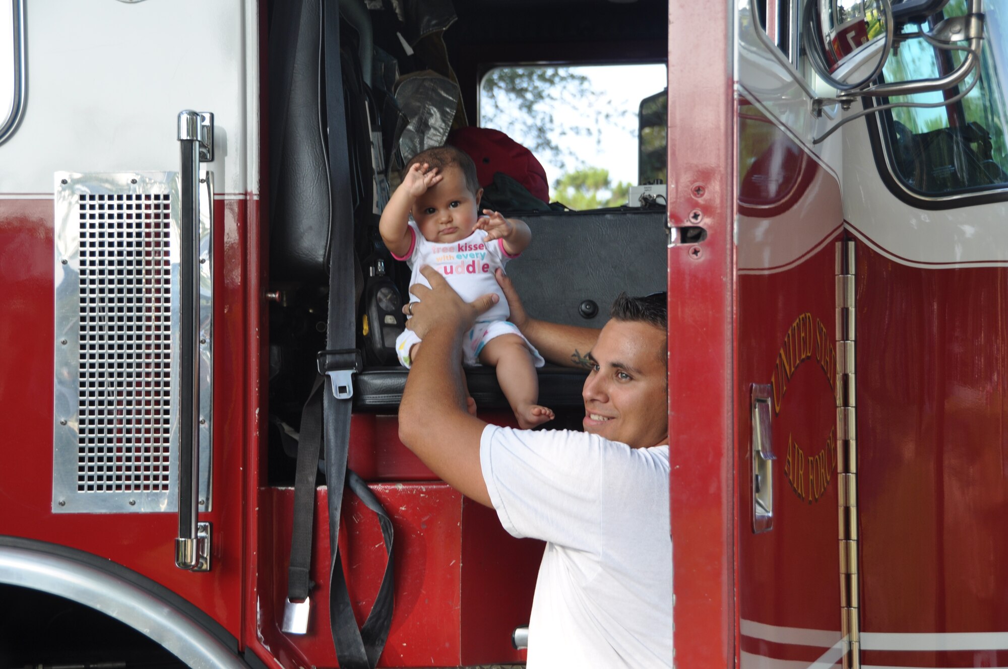 Senior Airman Michael Pike, 43rd Aircraft Maintenance Unit, sets his daughter Julissa Jasmine on the seat of a fire truck Aug. 2 during Tyndall's National Night Out event. Balfour Beatty Communities, Tyndall Community Police and Base Partners held the event to raise awareness about crime prevention at Tyndall.  (U.S. Air Force photo by Senior Airman Veronica McMahon)