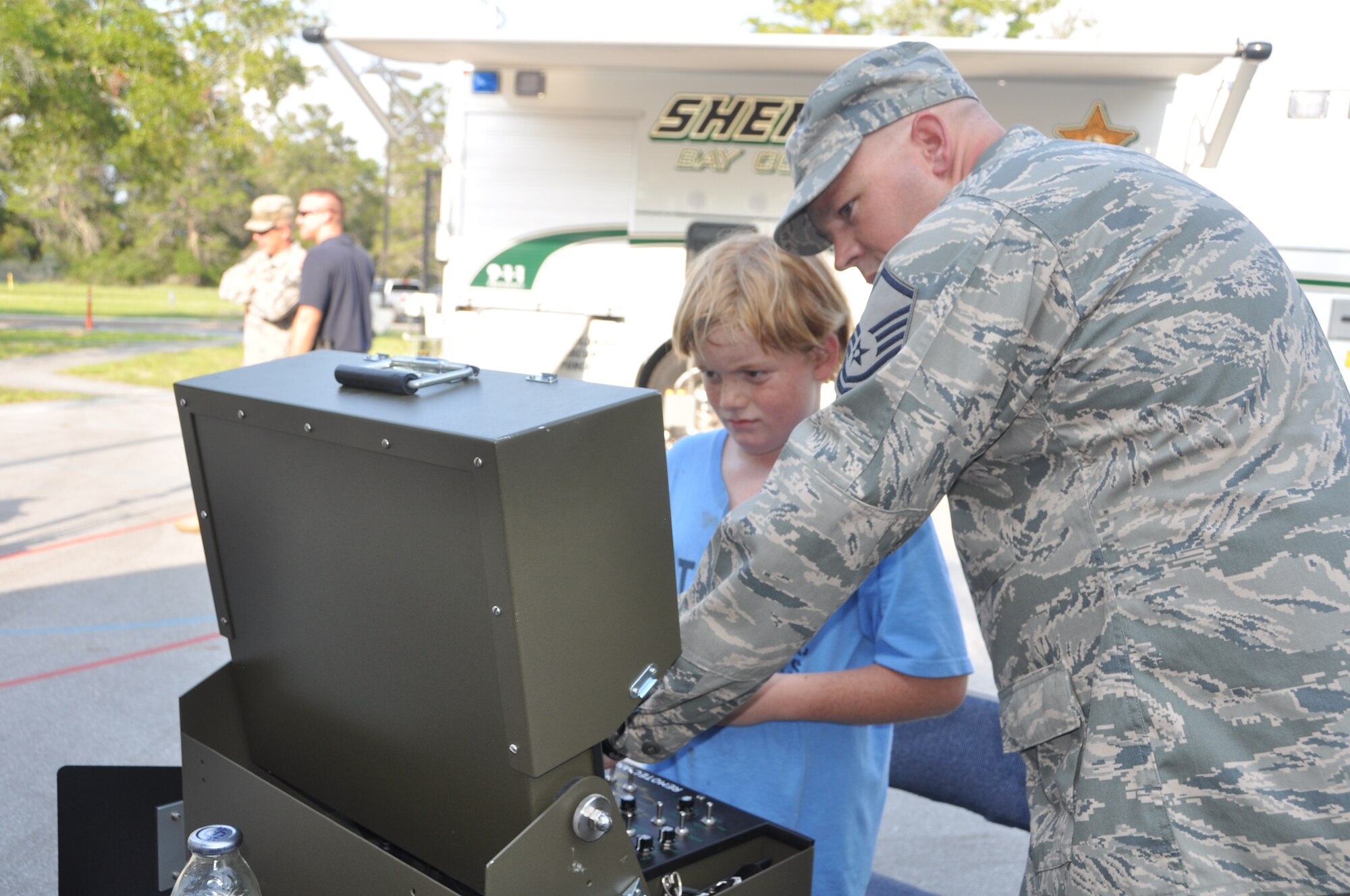 Master Sgt. Nathan Walch, 325th Civil Engineer Squadron, shows 9-year-old Mike Cederfeldt, how to work an Explosive Ordinance Device robot Aug. 2 during Tyndall AFB’s National Night Out event.  Balfour Beatty Communities, Tyndall Community Police and Base Partners held the event to raise awareness about crime prevention at Tyndall AFB.  (U.S. Air Force photo by Senior Airman Veronica McMahon)