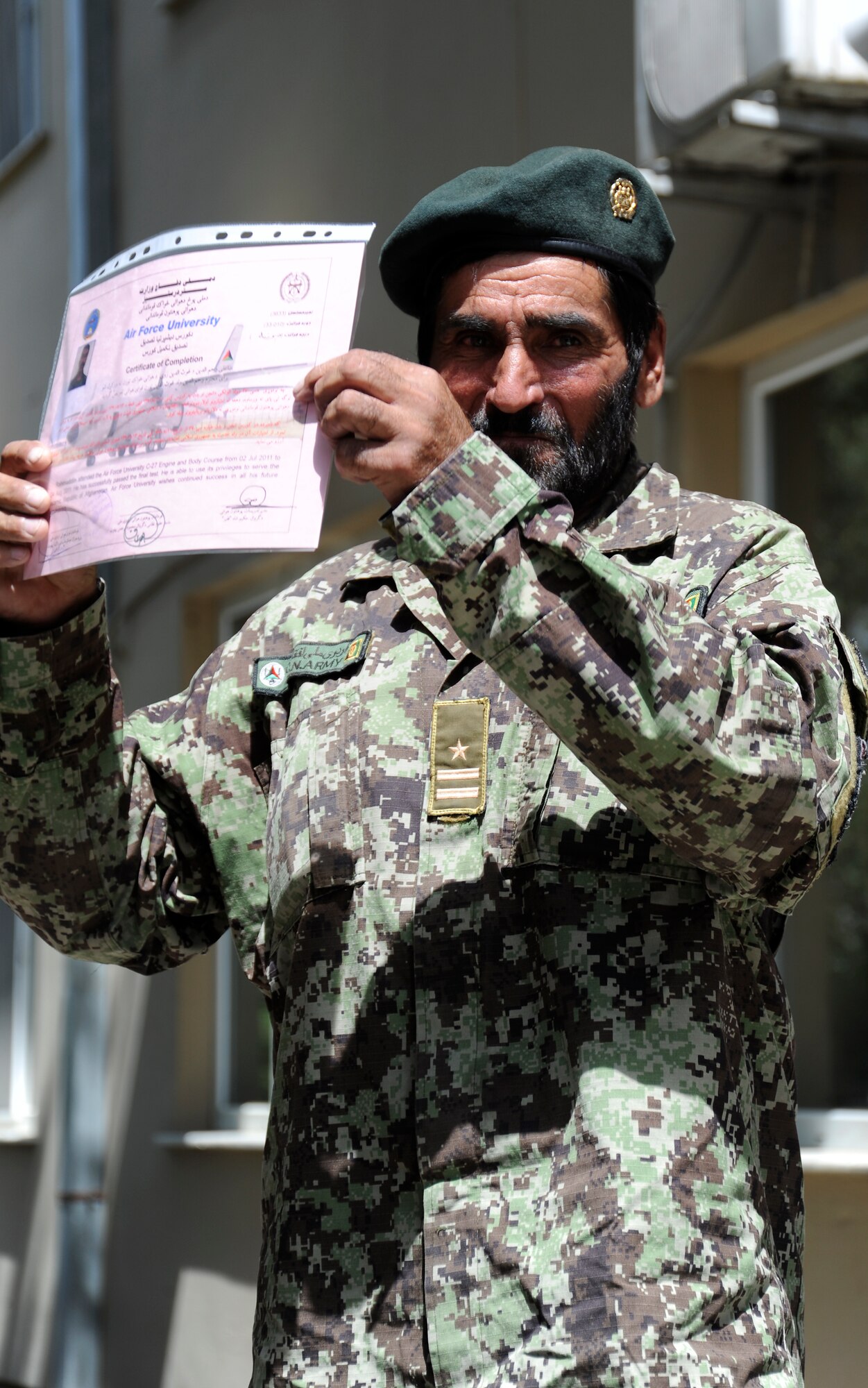 An Afghan Air Force airman holds up his certificate of graduation from the Afghan Air Force's "Big Air School," in Kabul, Afghanistan, Aug. 4, 2011. Graduates included members from air orientation class, security forces training, C-27 engine and body, logistics and mission planning. (U.S. Air Force photo by Staff Sgt. Matthew Smith)