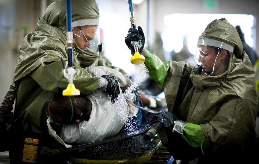 YOKOTA AIR BASE, Japan -- Capt Malisha Martukovich (right), 374th Aerospace Medicine Squadron audiologist, practices decontamination procedures by spraying a simulated victim with water at Yokota Air Base, Japan, during a emergency management exercise July 4, 2011. The exercise scenario centered around a simulated ?dirty bomb? explosion at the base fitness center. (U.S. Air Force photo/Staff Sgt. Samuel Morse)