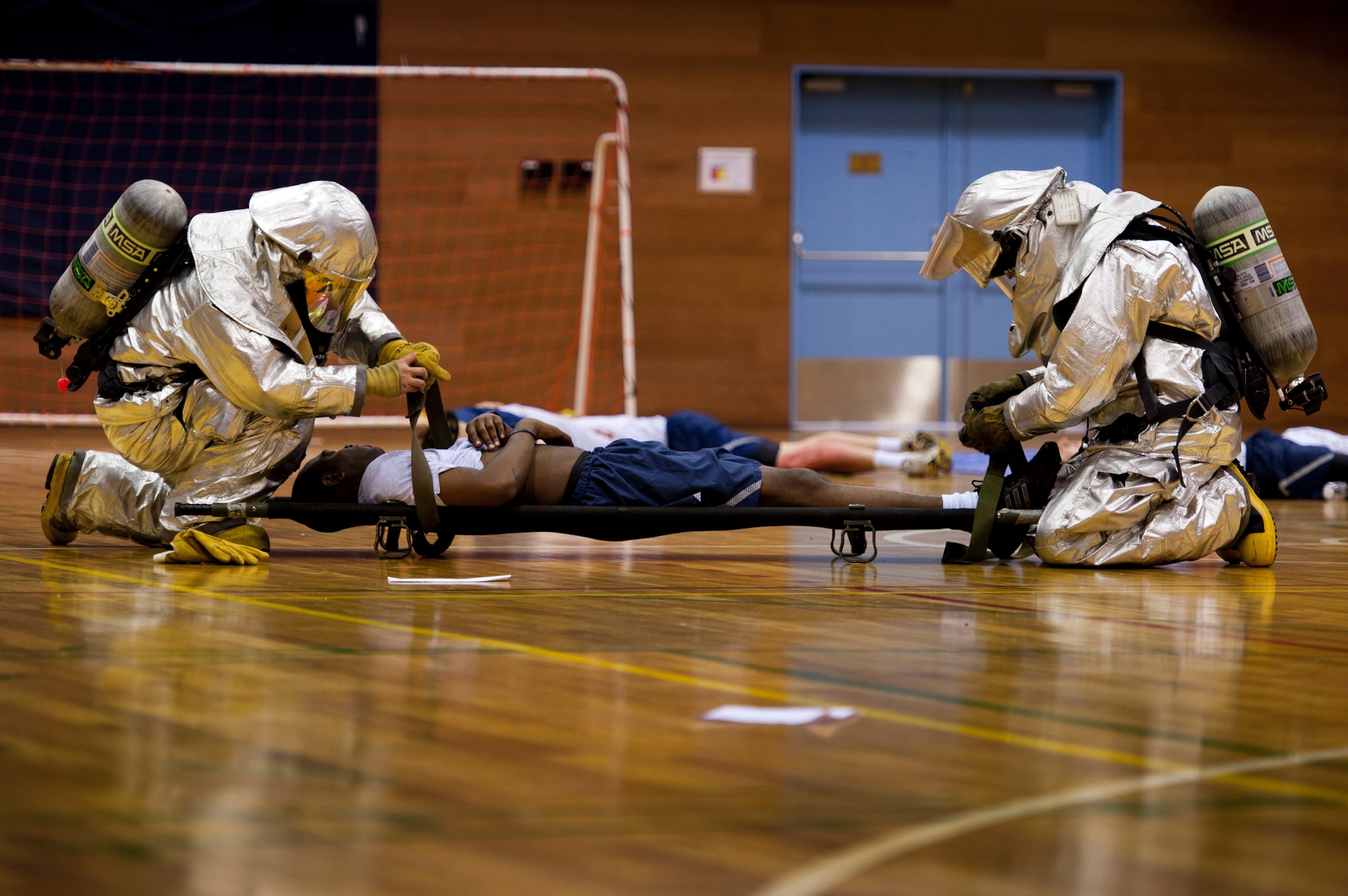 YOKOTA AIR BASE, Japan -- Firefighters with the 374th Civil Engineer Squadron strap a simulated explosion victim to a litter during an emergency management exercise at Yokota Air Base, Japan, Aug. 4, 2011. The exercise gave Yokota's emergency responders a chance to practice managing the various complexities of a mass casualty scenario. (U.S. Air Force photo/Staff Sgt. Samuel Morse)