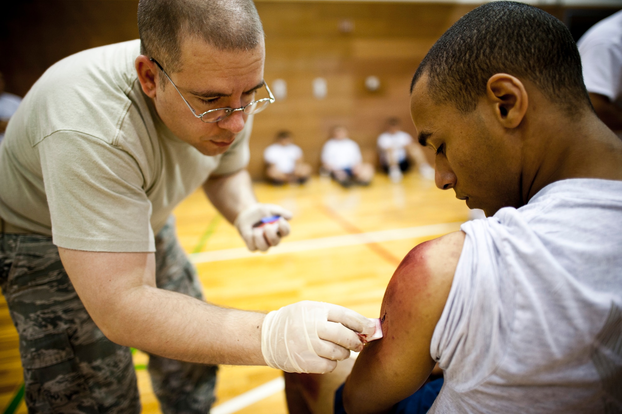 YOKOTA AIR BASE, Japan -- Master Sgt. Erik Baker, 374th Medical Support Squadron NCO in charge of medical material, applies moulage makeup to the shoulder of Airman 1st Class Derick Mason, a role player for an emergency management exercise at Yokota Air Base, Japan, Aug. 4, 2011. The makeup allows the exercise evaluation team to create the appearance of injuries on the role players to heighten the sense of realism during the exercise. (U.S. Air Force photo/Staff Sgt. Samuel Morse)