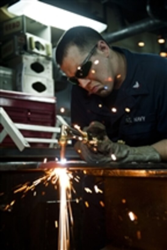U.S. Navy Petty Officer 3rd Class Jeffrey Meginness cuts sheet metal with an acetylene torch aboard the aircraft carrier USS John C. Stennis (CVN 74) in the Pacific Ocean on Aug. 3, 2011.  The John C. Stennis Carrier Strike Group is on a western Pacific Ocean and Arabian Sea deployment.  
