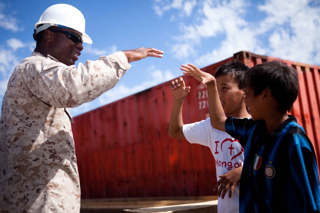 Petty Officer 2nd Class Kerlon Williams, hospital corpsman, 3rd Medical Battalion, III Marine Logistics Group, III Marine Expeditionary Force from Okinawa, Japan, performs a “pound and explode” handshake with local children during the Engineering Civic Action Program portion of Exercise Khaan Quest 2011 in Ulaanbaatar, Mongolia, Aug. 1. The purpose of the program is to improve medical care in the area by adding on to the Ayut Family Hospital, a 17,000 sq. ft. urgent care clinic, which will serve the 9th sub-district of khaan-Uul District. Khaan Quest is a training exercise designed to strengthen the capabilities of U.S., Mongolian and other participating nations’ forces in international peace support operations and civic outreach programs worldwide.