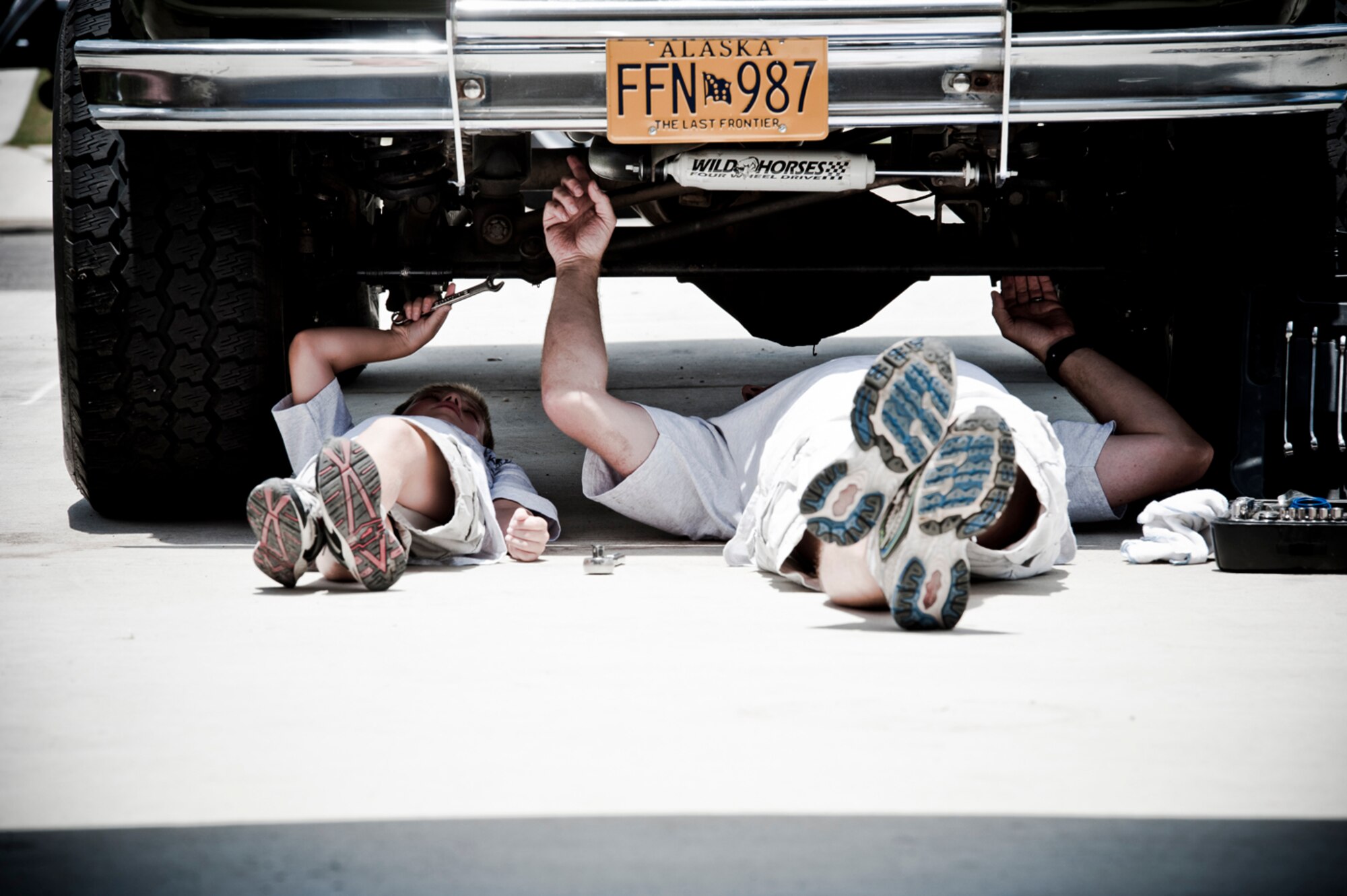 TEMPTED BY THE OTHER WOMAN - Like father, like son ,,, Meyer and his 6-year-old son, Noah, work underneath their Bronco, which they are constantly looking for ways to improve and upgrade. (Photo by TSgt Samuel Bendet)