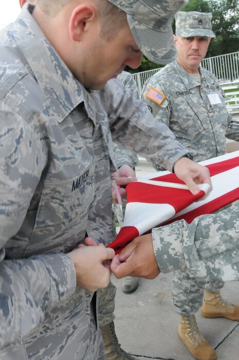 Air Force Staff Sgt. Seth Mayer helps fold the flag after a flag ceremony held during Freedom Academy.  Each morning, students participated in raising the flag and reciting the pledge of allegience as they spent the week learning more about the meaning of freedom.  (U.S. Army photo by Sgt. Shana Hutchins)