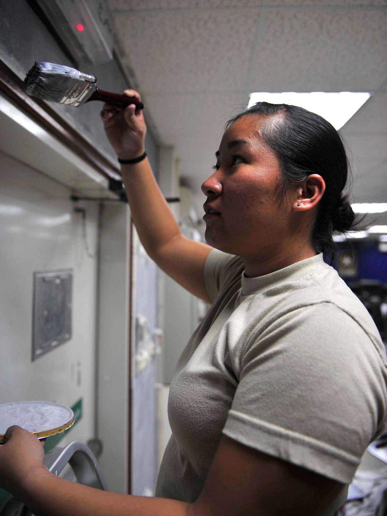 Senior Airman Trisha Leong, deployed to the 380th Air Expeditionary Force Support Squadron in Southwest Asia, paints part of the Chapman Activity Center Aug. 6, 2011. The staff of the CAC is in the final stages of a remodeling project that will provide a more relaxing atmosphere for deployed Airmen and Soldiers at 380th Air Expeditionary Wing and will give folks more morale and welfare opportunities. (U.S. Air Force photo/Staff Sgt. Patrick Mitchell)