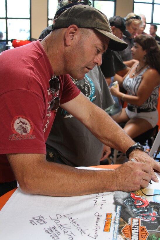 Marc Lemieux, Clairemont Mesa, Calif. signs a t-shirt that El Cajon Harley Davidson had set out during their fundraiser Aug. 6. Attendees were able to sign the t-shirts, a book with their own personal message and donate money to Gunnery Sgt. David Smith who was recently injured in a motorcycle accident.