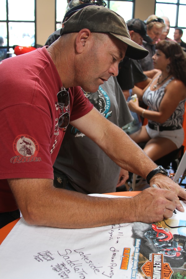 Marc Lemieux, Clairemont Mesa, Calif. signs a t-shirt that El Cajon Harley Davidson had set out during their fundraiser Aug. 6. Attendees were able to sign the t-shirts, a book with their own personal message and donate money to Gunnery Sgt. David Smith who was recently injured in a motorcycle accident.