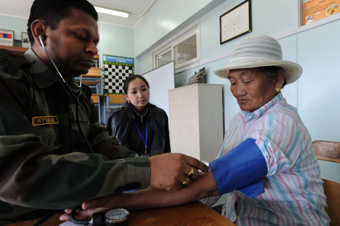 Maj. Atul Goel, a doctor with the Indian Army, takes the blood pressure of a Mongolian woman during a check-up at the temporary clinic held in the Buynt Uhaa Complex in Ulaanbaatar, Mongolia on Aug. 7 during Khaan Quest 2011, a combined joint-exercise hosted by the Mongolian Armed Forces in partnership with U.S. Pacific Command forces.  Khaan Quest is in its eighth year and has military participants from Canada, India, the Republic of Korea, the United States, Mongolia and others. In addition to a medical civic action event, there is an engineering outreach event, a Command Post exercise and several field exercises. Khaan Quest officially started July 31 and continues until Aug 12.