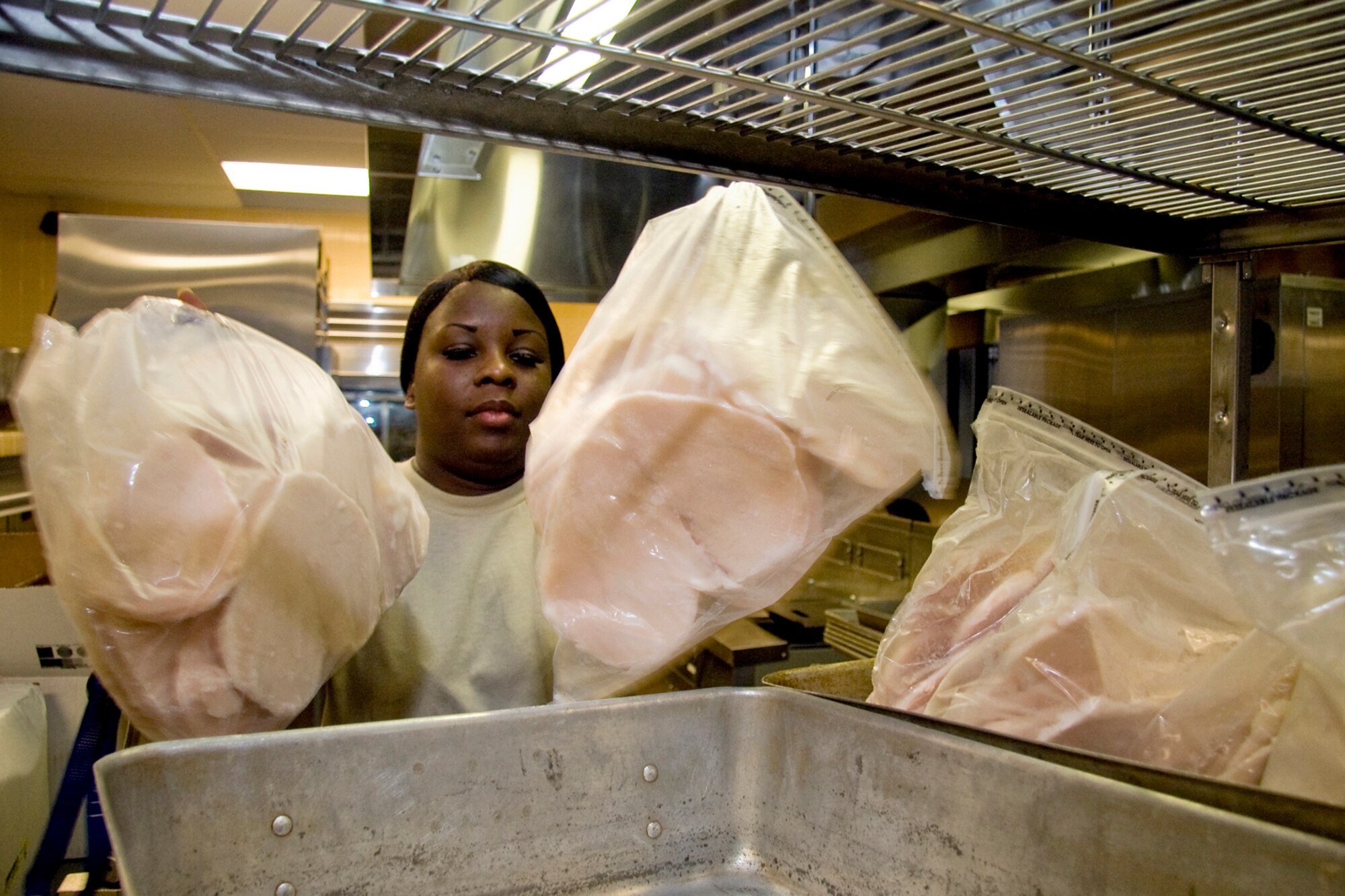 GRISSOM AIR RESERVE BASE, Ind. -- Staff Sgt. Danielle Taylor, 434th Force Support Squadron store room manager, puts breasts of chicken into a pan to thaw prior to a unit training assembly Aug. 4. Taylor is responsible for the ordering, stocking, managing and initial preparation for all food consumed by reservists during UTAs. (U.S. Air Force photo/Tech. Sgt. Mark R. W. Orders-Woempner)
