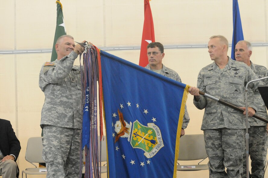 Maj. Gen. David A. Sprynczynatyk, N.D. Adjutant General, left, places an Outstanding Unit Award streamer on the 119th Wing flag as Wing Commander  Col. Rick Gibney lowers the flag into place while Brig. Gen. Cecil "Bud" Hensel, the North Dakota National Guard Joint Force Headquarter Air Component Commander, center, and Chief Master Sgt. David Harmon, the 119th Wing command chief, far right, look on at the North Dakota Air National Guard, Fargo, N.D., Aug. 6.  It is the fourteenth time the unit has won the Air Force Outstanding Unit Award which is awarded annually to units which have made achievements of national or international significance, successful involvement with combat and military operations or exposure to hostile actions by an opposing foreign force. (DoD photo by Senior Master Sgt. David H. Lipp) (Released)