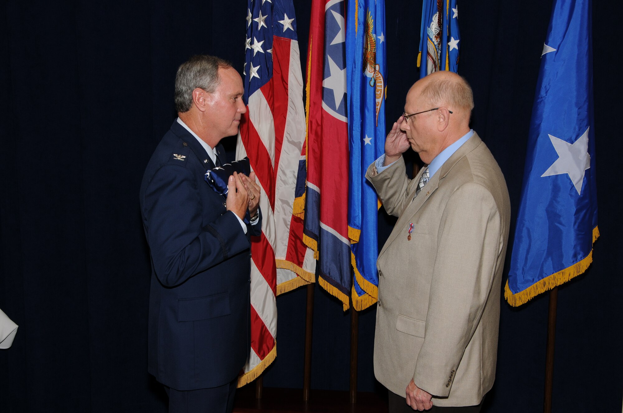 Colonel Harry D. Montgomery, 164th Airlift Wing Commander, presents the American Flag that was flown on Colonel Spencer's last duty day to Lieutenant Colonel Lamar Spencer during Col Spencer's retirement ceremony.
