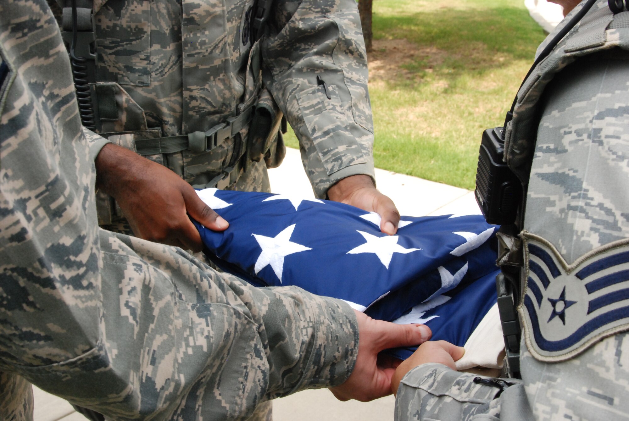 Members of the flag detail work together to fold the flag into triangular sections. At the end of the process, the only thing that’s visible is a triangular blue field of stars. (U.S. Air Force photo/Airman 1st Class Chelsea Smith)
