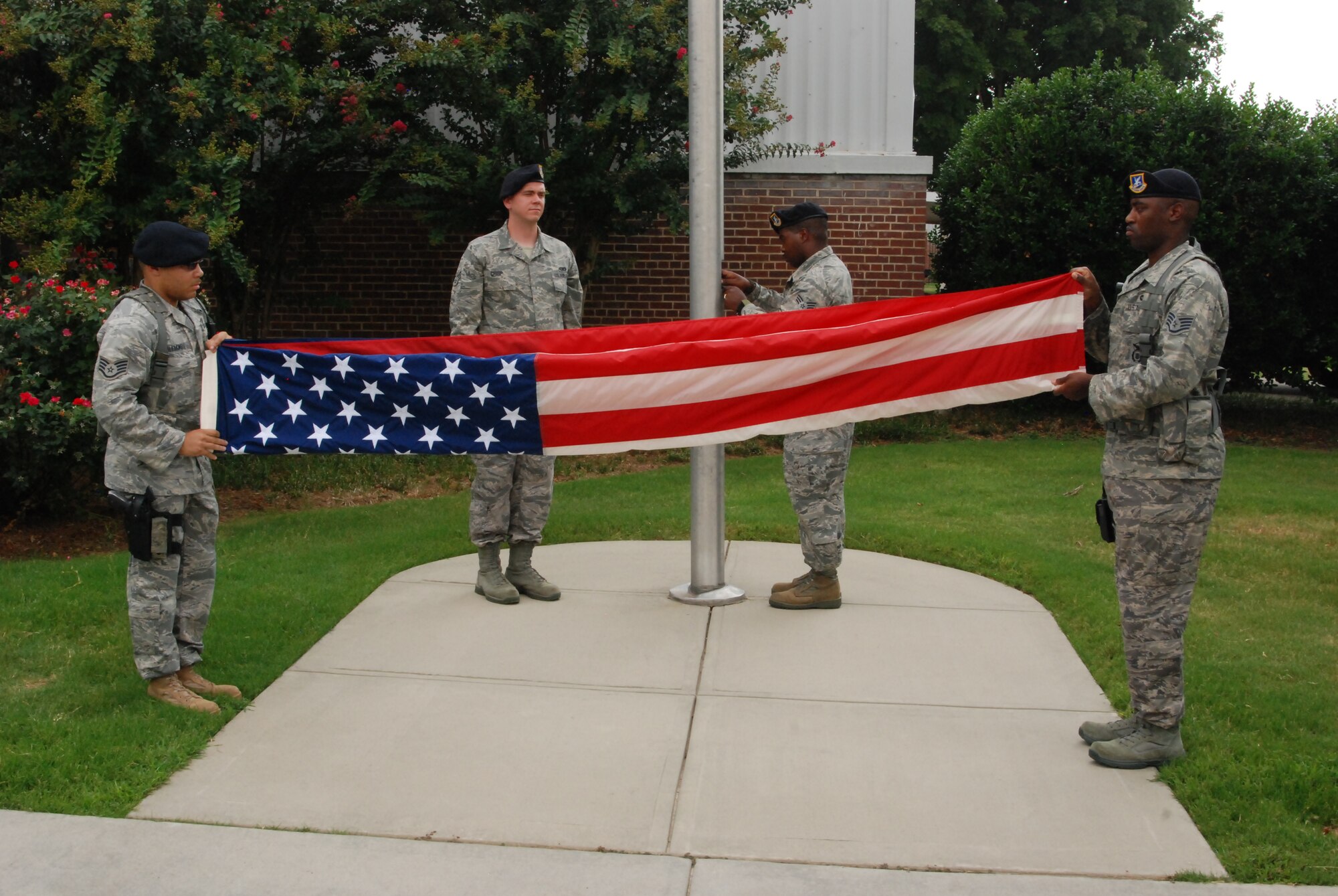 Staff Sgts. Devontay Williams and Charles Cornelius from the 94th Airlift Wing security forces squadron, begin folding the flag after it has been lowered. Folding of the flag includes evenly securing the edges of the flag and making triangular folds until the only thing that’s visible is a triangular blue field of stars. (U.S. Air Force photo/Airman 1st Class Chelsea Smith)