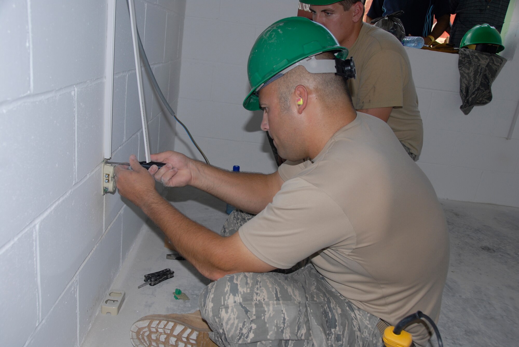 PARAMARIBO, SURINAME - Staff Sgt. Zach Jorgensen, a craftsman with the 114th Fighter Wing's Civil Engineer Squadron,  shows Senior Airman Andrew Peterson how to install an electrical outlet in the Alkmaar Clinc being built in the Commewijne district here July 13, 2011.  The 114th is helping build one of  two clinics that are scheduled to be built during New Horizons Suriname.  (Air Force Photo by Tech. Sgt. Quinton Young)(RELEASED) USAF