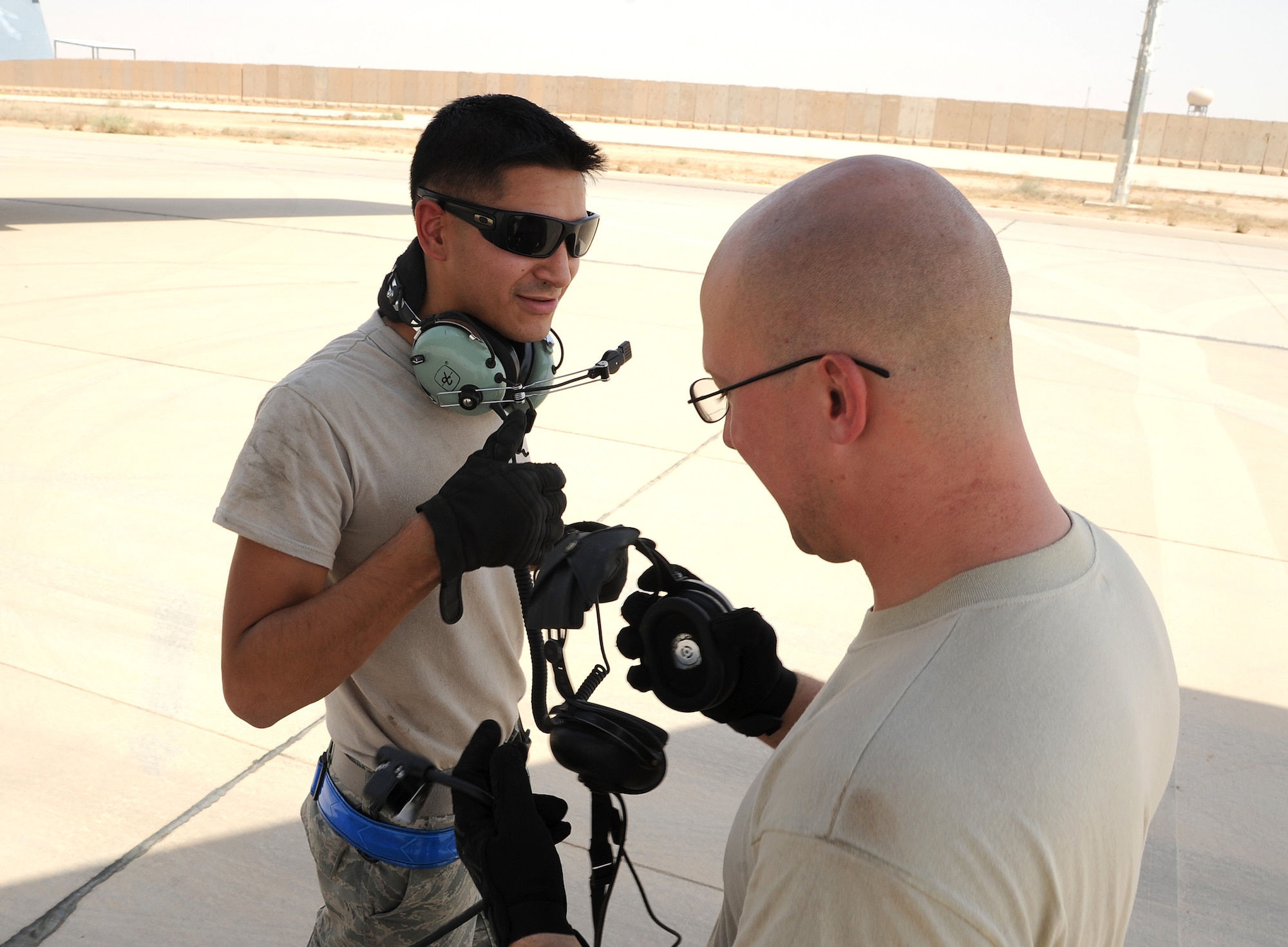 Air Force Senior Airmen Binh Martz, 340th Expeditionary Aircraft Refueling Squadron aircraft hydraulics journeyman, and David Manning, 340th EARS jet engine mechainc, exchange headphones during the pre-inspection phase before take off in Southwest Asia. Communication with pilots in the cockpit lets mechanics know if anything is wrong before take off. (U.S. Air Force photo by Senior Airman Tristin English)