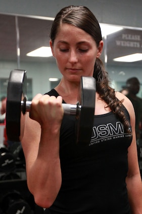 First Lt. Jennifer Silvers, the Marine Fighter Attack Squadron 122 material control officer, does bicep curls at the Air Station Fitness Center, Aug. 8. Since Silvers has started weightlifting she has felt more energy, her body feels stronger and she has stronger mental endurance.
