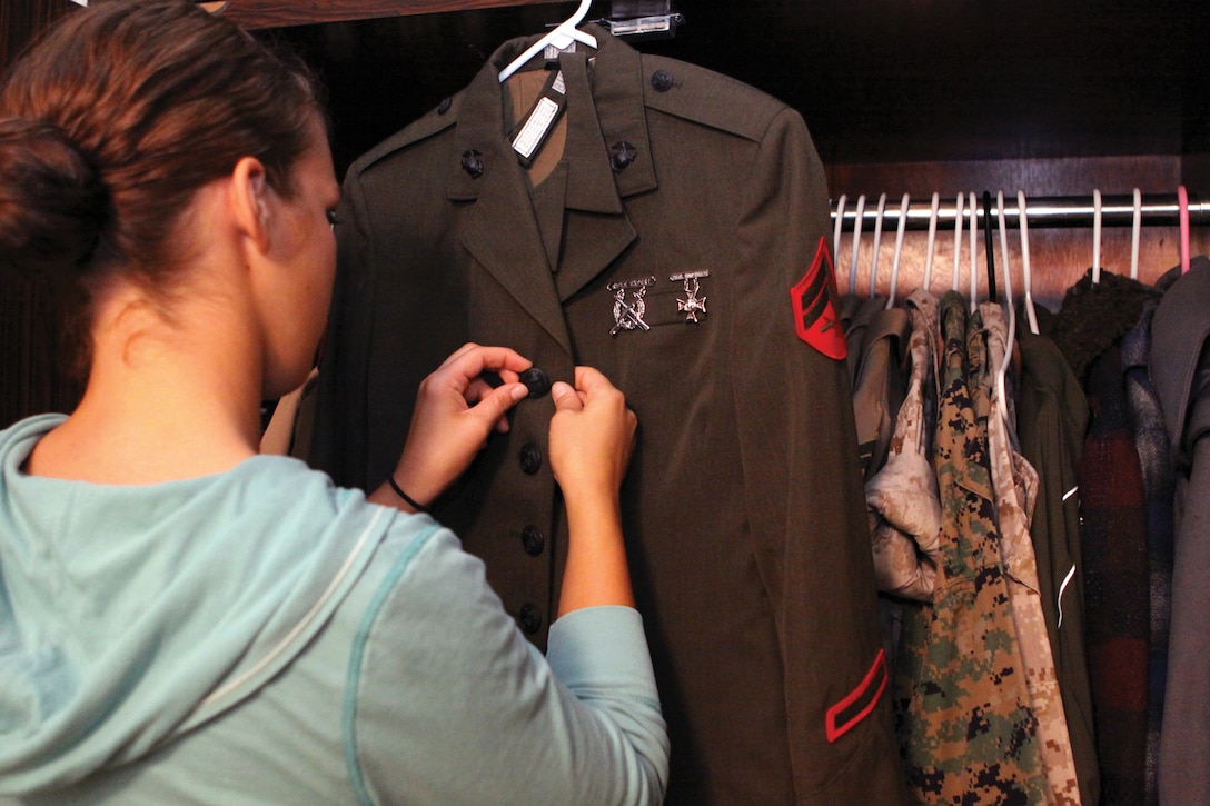 A Marine looks over her service alphas uniform before storing it in a closet. While in the Inactive Ready Reserves, Marines must maintain their uniforms.