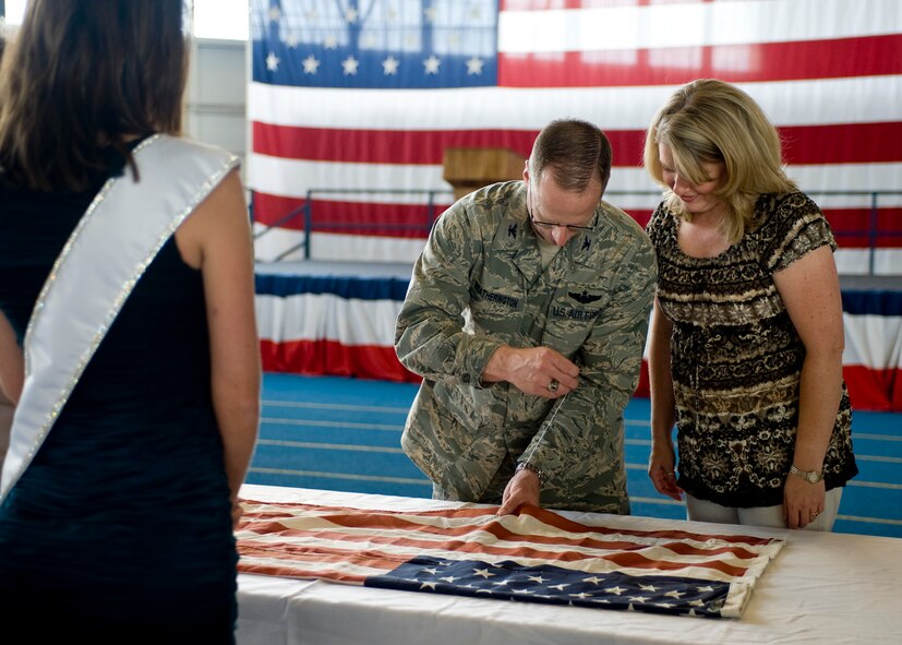 Col. Mark Weatherington, 28th Bomb Wing commander, sews a stitch into the flag as his wife, Stephanie, watches on during the start of a special 9/11 flag stitching event at Ellsworth Air Force Base, S.D., Aug. 4, 2011. The Weatheringtons were the first of more than 150 Airmen and family members who added stitches to the flag during the event.  (U.S. Air Force photo/Airman Alystria Maurer/Released)