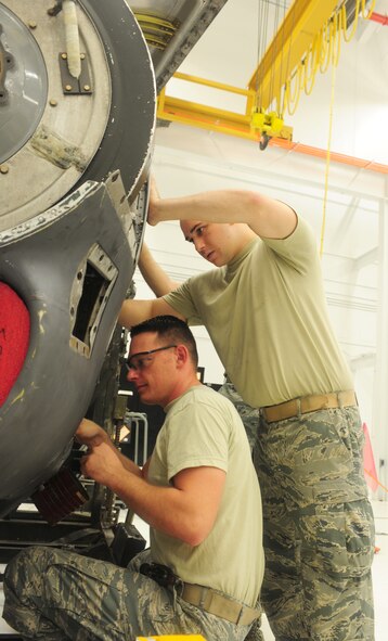 U.S. Air Force Airman 1st Class Gregory Thornton, left, 23rd Component Maintenance Squadron aerospace propulsion apprentice, safety wires the line of a T-56 engine to prevent the line from coming off during the engine vibration as Staff Sgt. Caleb Castillo, 23rd CMS aerospace propulsion craftsman, answers Thornton’s questions at Moody Air Force Base, Ga., Aug. 8, 2011. Castillo has been at Moody for eight years and has deployed five times, so he has plenty of experience to share with the newer Airman. (U.S. Air Force photo by Senior Airman Stephanie Mancha/Released)