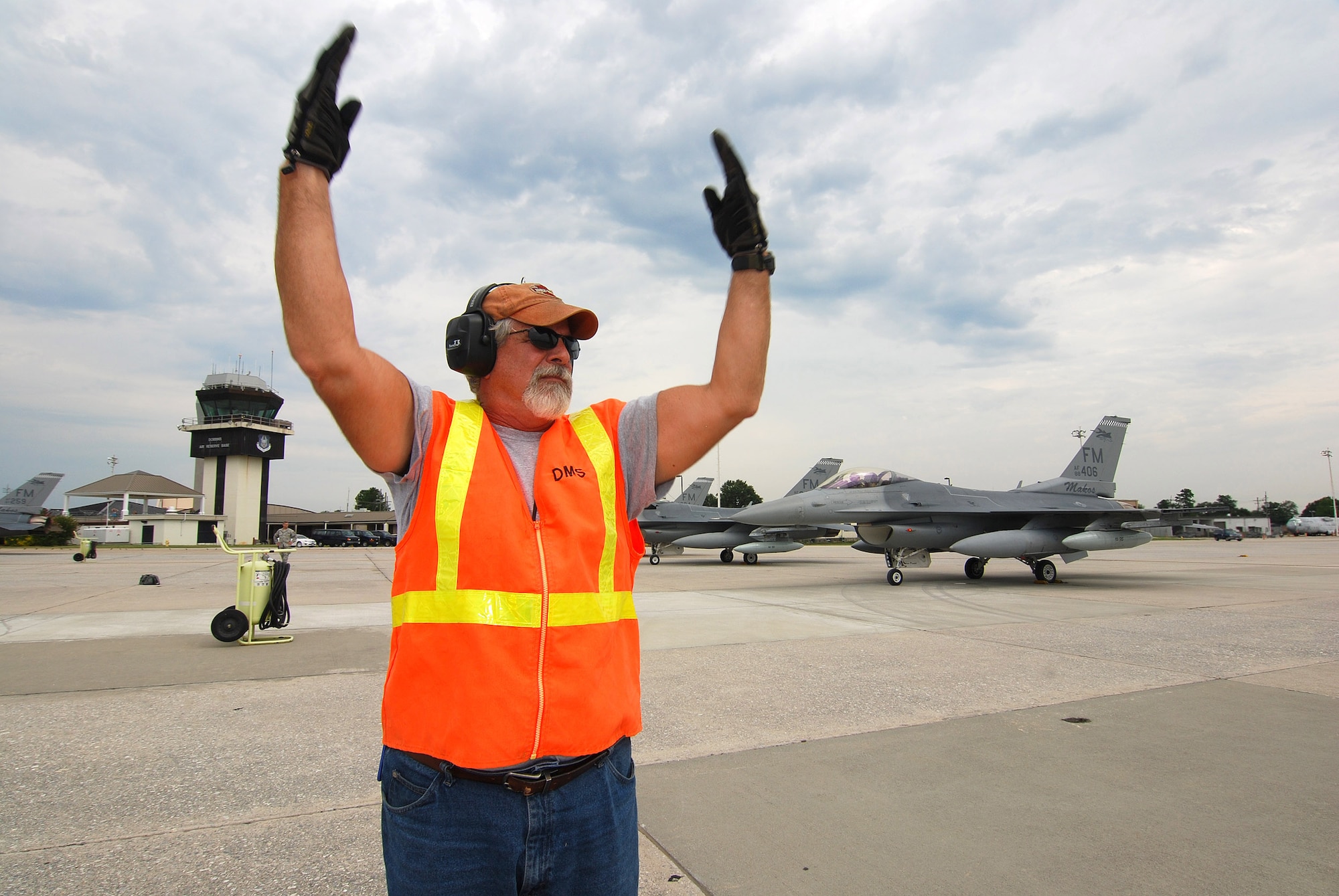 Melvin Woods catches the attention of the next arriving F-16C pilot so he can marshal him into a parking space on the Dobbins Air Reserve Base ramp, Aug 4. Mr. Woods is a member of the Transient Alert team responsible for guiding visiting aircraft arriving and departing Dobbins ARB. The F-16C block 30 fighter jets are being moved from Homestead ARB as a precautionary measure to avoid possible damage from tropical storm Emily, currently brewing in the Atlantic Ocean.  (U.S. Air Force photo/ Brad Fallin)