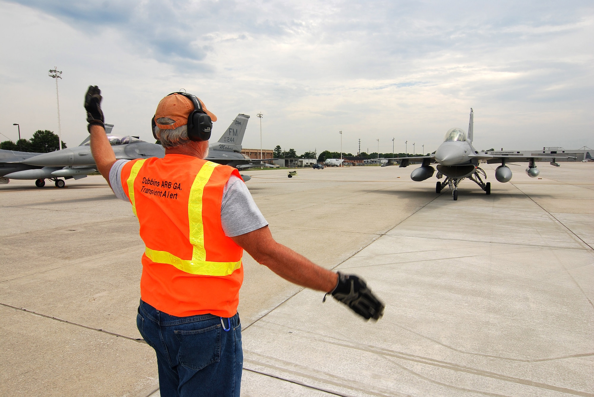 Melvin Woods marshals an arriving F-16C aircraft into a parking space on the Dobbins Air Reserve Base ramp, Aug 4. Mr. Woods is a member of the Transient Alert team responsible for guiding visiting aircraft arriving and departing Dobbins ARB. The F-16C block 30 fighter jets are being moved from Homestead ARB as a precautionary measure to avoid possible damage from tropical storm Emily, currently brewing in the Atlantic Ocean.  (U.S. Air Force photo/ Brad Fallin)