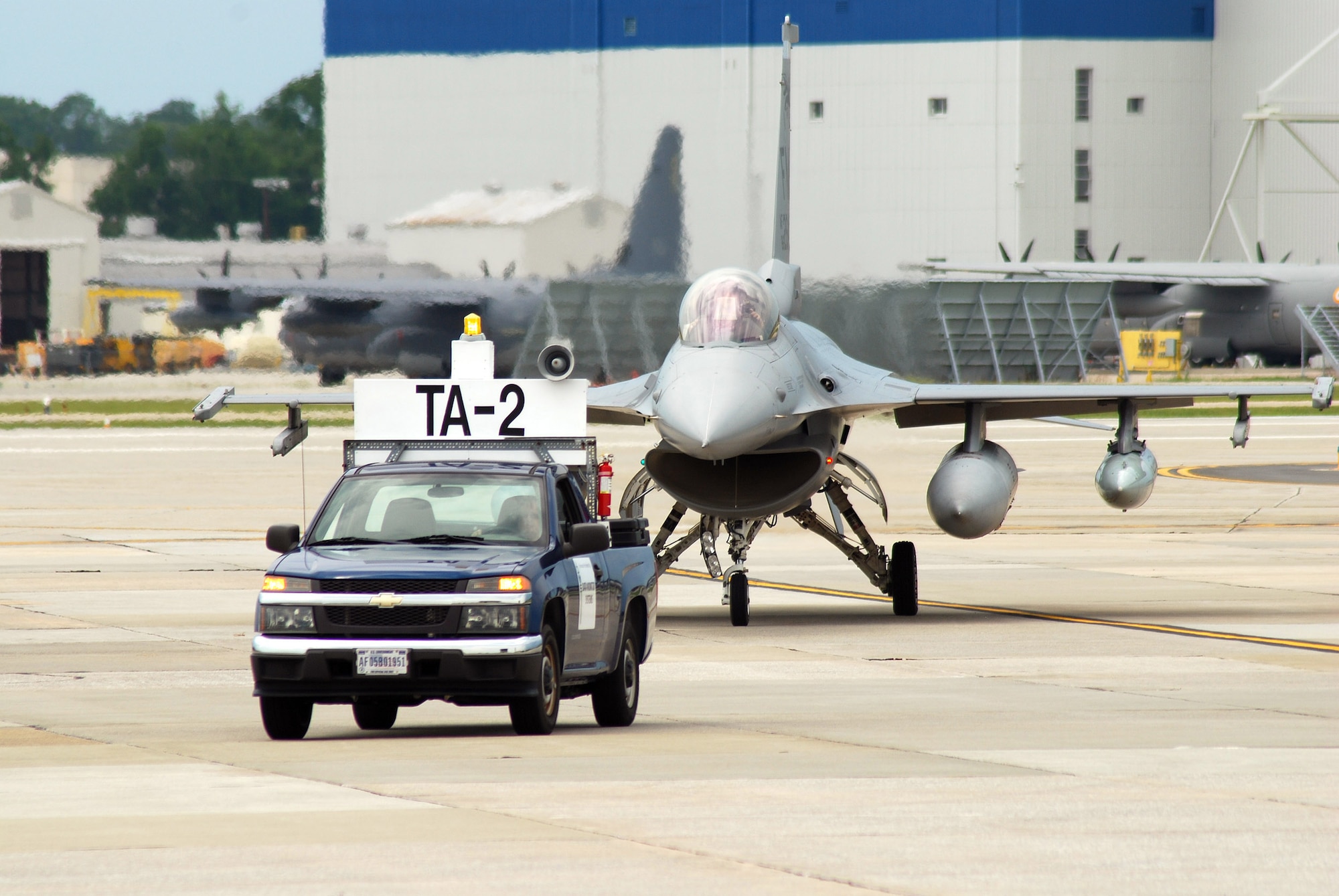 A Transient Alert truck guides an arriving F-16C aircraft to a parking space on the Dobbins Air Reserve Base ramp, Aug 4. The Transient Alert team are responsible for guiding visiting aircraft arriving and departing Dobbins ARB. The F-16C block 30 fighter jets are being moved from Homestead ARB as a precautionary measure to avoid possible damage from tropical storm Emily, currently brewing in the Atlantic Ocean.  (U.S. Air Force photo/ Brad Fallin)