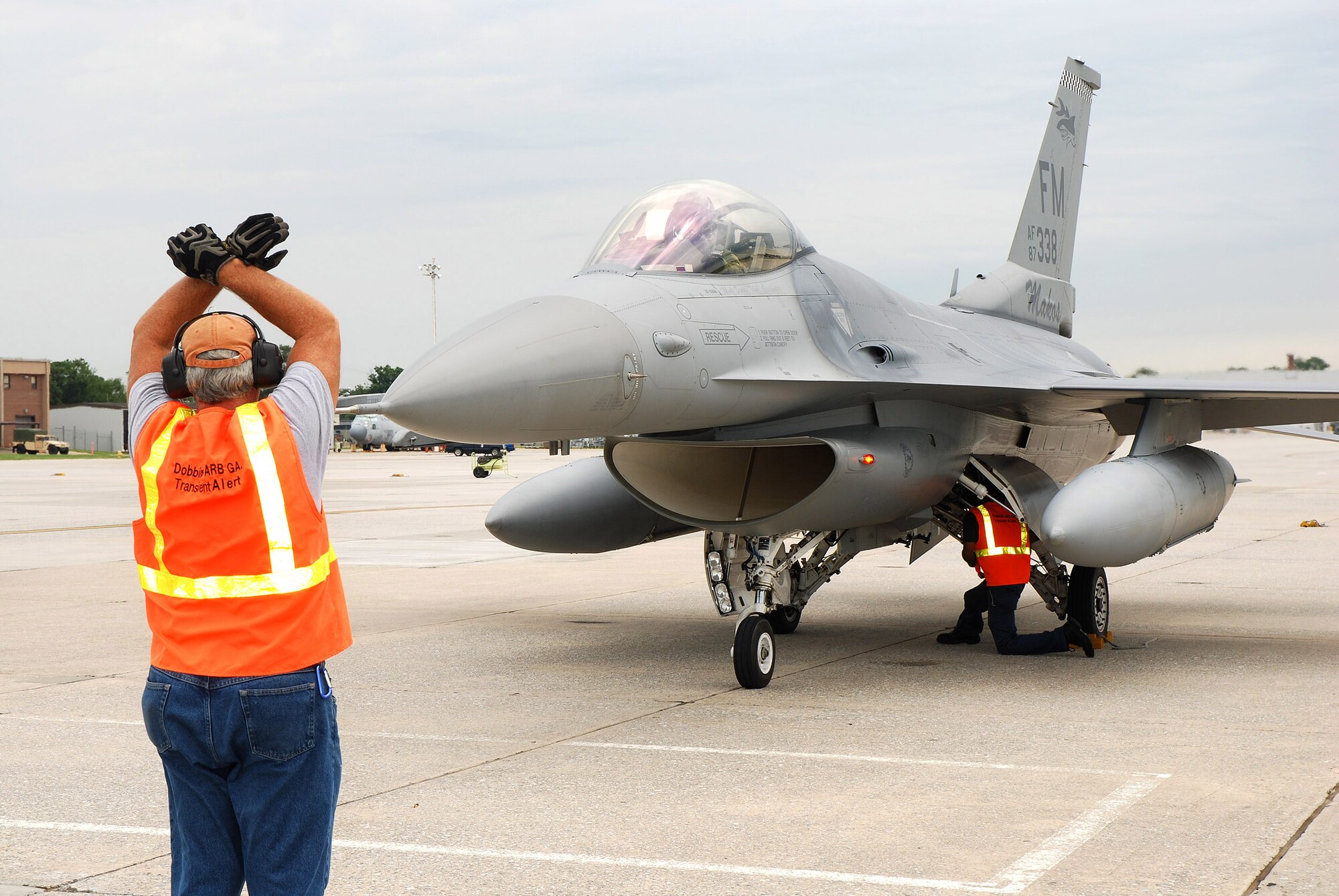 Melvin Woods signals an arriving F-16C pilot to hold brakes on his aircraft as it is being readied to park on the Dobbins Air Reserve Base ramp, Aug 4. Mr. Woods is a member of the Transient Alert team responsible for guiding visiting aircraft arriving and departing Dobbins ARB. The F-16C block 30 fighter jets are being moved from Homestead ARB as a precautionary measure to avoid possible damage from tropical storm Emily, currently brewing in the Atlantic Ocean.  (U.S. Air Force photo/ Brad Fallin)