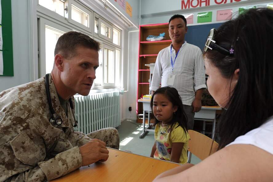 ULAANBAATAR, Mongolia ? U.S. Navy doctor, Commander Steve Kriss, a member of 3rd Marine logistics, Camp Kinser, Okianwa, Japan, speaks with a Mongolian woman  about what is ailing her young daughter during an exam at the temporary clinic held in the Buynt Uhaa Complex in Ulaanbaatar, Mongolia on Aug. 7 during Khaan Quest 2011, a combined joint-exercise hosted by the Mongolian Armed Forces in partnership with U.S. Pacific Command forces.  Khaan Quest is in its eighth year and has military participants from Canada, India, the Republic of Korea, the United States and Mongolia. In addition to a medical civic action event, there is an engineering outreach event, a Command Post exercise and several field exercises. Khaan Quest officially started July 31 and continues until Aug 12.  (U.S.  Air Force photo/Master Sgt. Cohen A. Young)