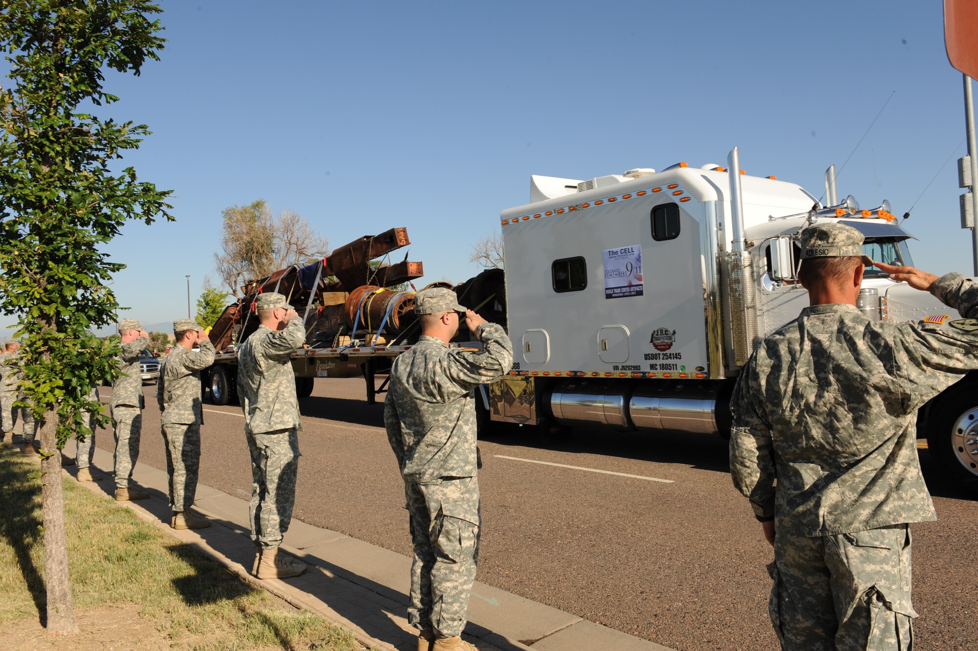 BUCKLEY AIR FORCE BASE, Colo. -- Soldiers of the Colorado Army National Guard salute artifacts from the World Trade Center as it is transported from Buckley AFB to downtown Denver, Colo., Aug. 8, 2011. These steel pieces, weighing more than 230,000 pounds, will be the center of memorials around the city. (U.S. Air Force photo by Senior Airman Marcy Glass)