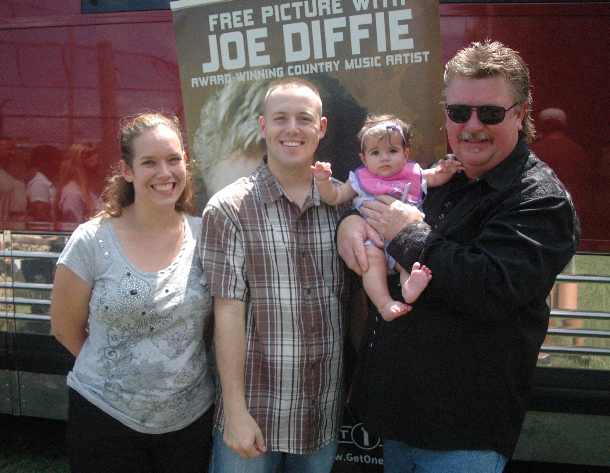 Country music star Joe Diffie poses for a photo with Tech. Sgt. Rodney Douglas, 512th Maintenance Squadron, his daughter Braleyn, and wife Katie at the 512th Airlift Wing biennial picnic Aug. 6 at Eagle?s Nest. The Air Force Reserve sponsored the musician as part of the Get One Now program, a recruiting tool reservists can use to refer people interested in joining the AF Reserve. More than 2,000 people attended the event. (U.S. Air Force photo by Master Sgt. Veronica Aceveda)
