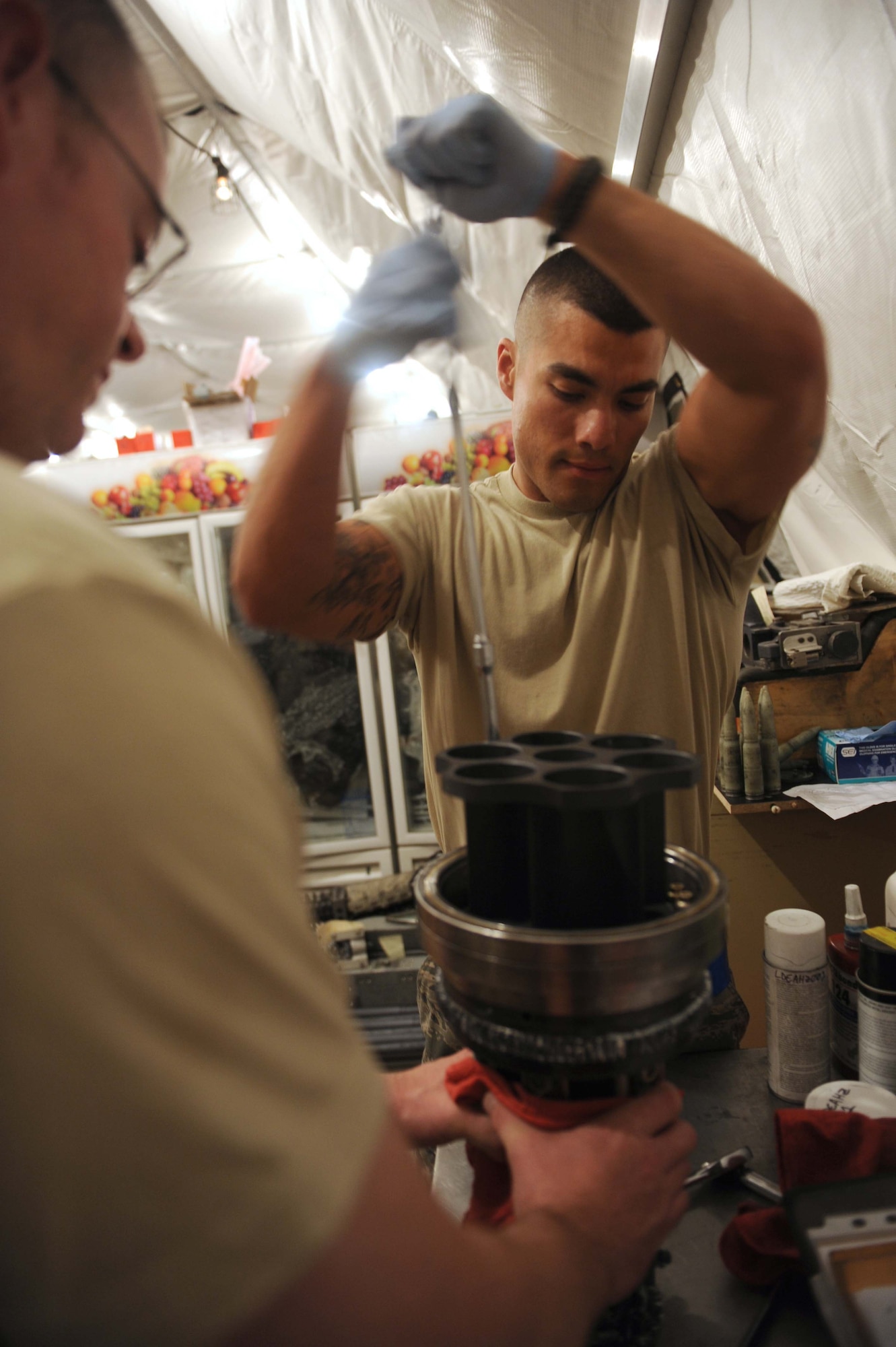 Senior Airman Edgar Pardo, 380th Expeditionary Aircraft Maintenance Squadron, aircraft armament system journeyman, and Tech. Sgt. Calyn Coffee, 380th EAMXS, NCO in charge of armament, dismantle part of the M61A1 20-millimeter gatling gun system Aug. 4, 2011. Pardo and Coffee are two of eight Airmen in the F-15 Eagle armament shop at the 380th Air Expeditionary Wing in Southwest Asia. (U.S. Air Force photo/Master Sgt. Chance Babin)