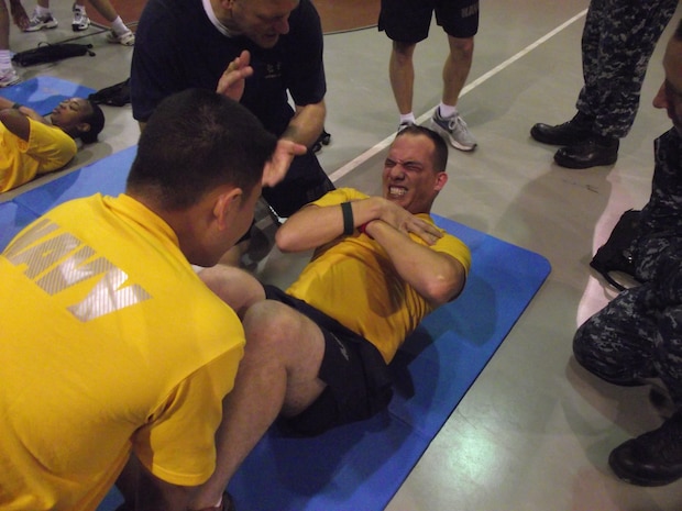 Chief Petty Officer selectee MM1 Christopher Huggins crunches out another sit up during morning physical training at Joint Base Charleston - Weapons Station last week. Physical training is a key component of Chief Petty Officer Induction. Besides ensuring the Navy's newest chiefs are physically fit, PT provides an opportunity for the chief selectees to work alongside seasoned CPOs to build teamwork and camaraderie.  (U.S. Navy photo/Ira Holmes)