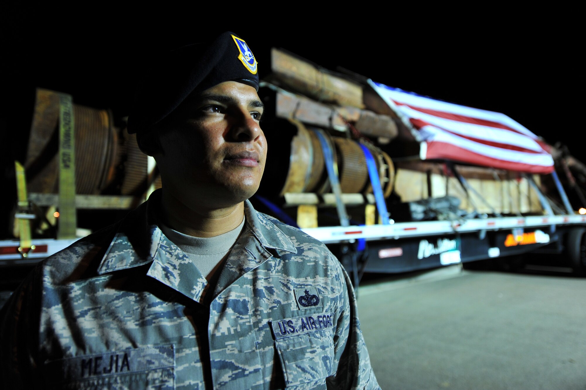 BUCKLEY AIR FORCE BASE, Colo. -- Staff  Sgt. Brandon Mejia, 460th Security Forces Squadron, stands in front of pieces of the World Trade Center Aug. 7, 2011. The 230,000 pounds of rusted steel stopped at Buckley AFB overnight on its way to its final destination in downtown Denver, Colo. Mejia will keep vigil over the shipment until dawn. (U.S. Force photo by Staff Sgt. Kathrine McDowell)