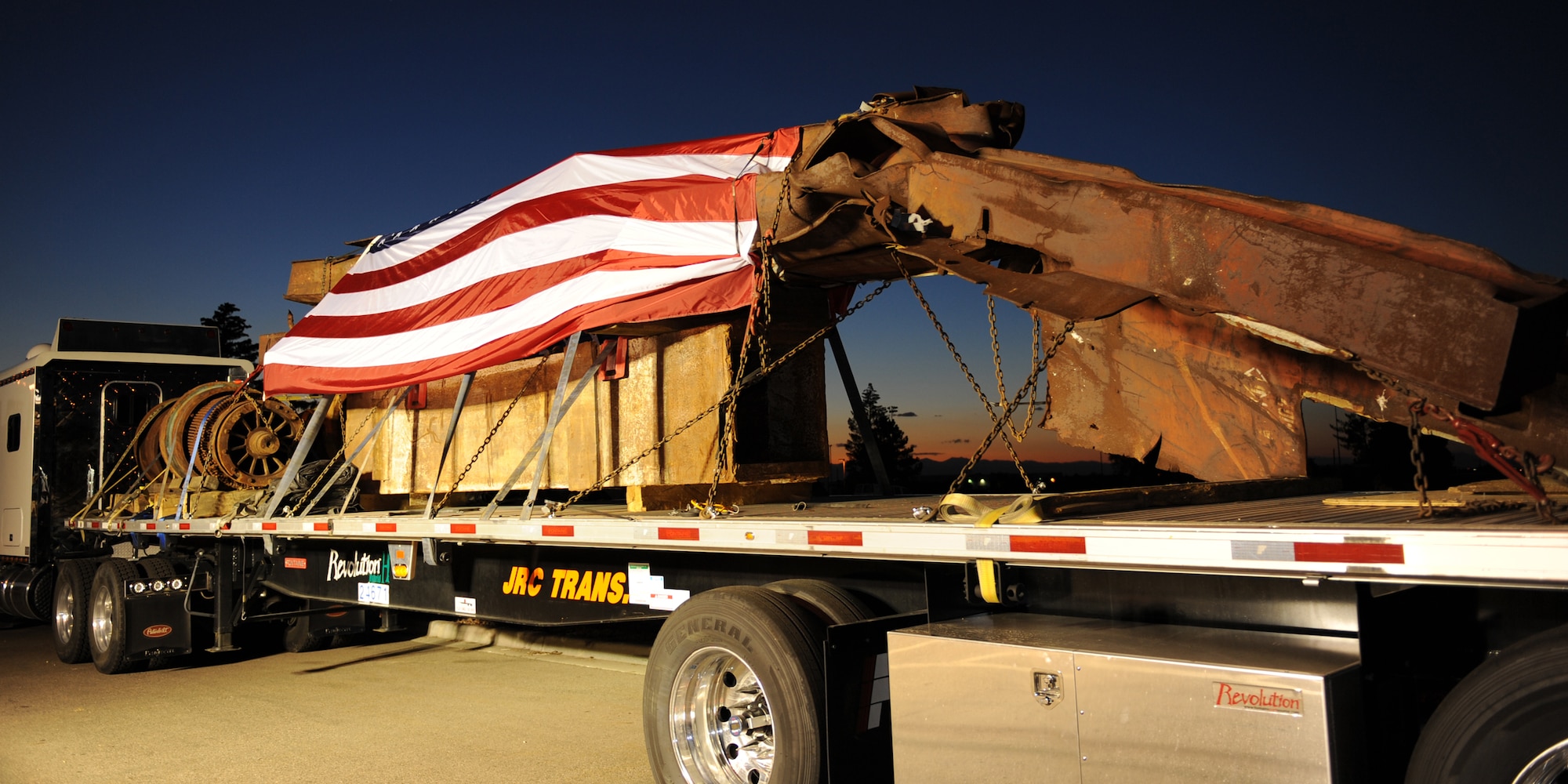 BUCKLEY AIR FORCE BASE, Colo. --  A flag drapes pieces of steel from the top five floors of the World Trade Center Aug. 7, 2011. Resting at Buckley AFB, pieces from the Port Authority of New York and New Jersey are being transported across the nation to commemorate the 10th anniversary of 9/11. (U.S. Air Force photo by Senior Airman Marcy Glass)
