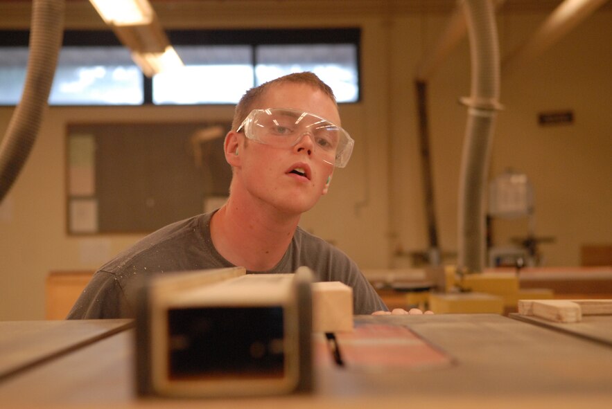 KUNSAN AIR BASE, Republic of Korea -- Senior Airman Philip Bennett, 8th Maintenance Operations Squadron weapons standardization load crew member, checks the height of the table saw blade before making a cut at the wood shop here Aug. 3. Bennett is using the wood shop to build a dartboard for his squadron that will double as a bulletin board in his office. (U.S. Air Force photo/Master Sgt. Sonny Cohrs)