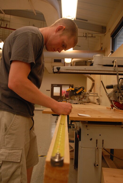 KUNSAN AIR BASE, Republic of Korea -- Senior Airman Philip Bennett, 8th Maintenance Operations Squadron weapons standardization load crew member, marks wood for a cut while building a dartboard for his unit Aug. 3. (U.S. Air Force photo/Master Sgt. Sonny Cohrs)