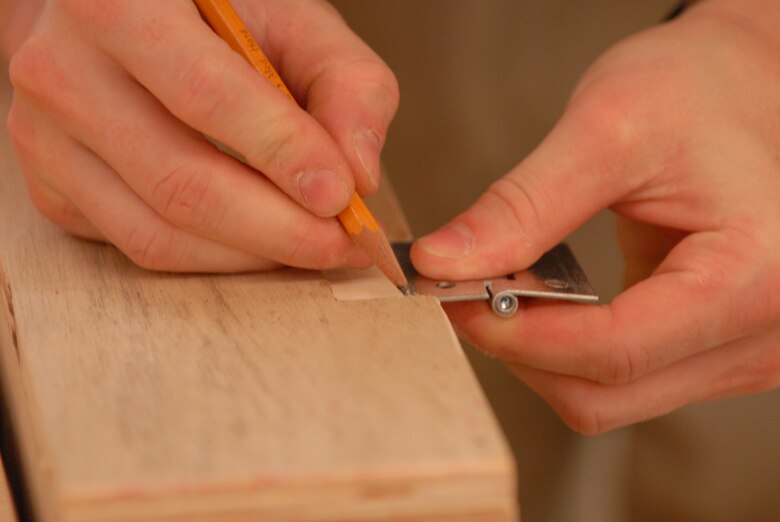 KUNSAN AIR BASE, Republic of Korea -- Senior Airman Philip Bennett, 8th Maintenance Operations Squadron weapons standardization load crew member, marks the wood to place a hinge in a dartboard case he’s building at the Arts and Crafts Center’s wood shop here Aug. 3. (U.S. Air Force photo/Master Sgt. Sonny Cohrs)