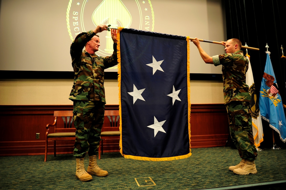 Navy Adm. William H. McRaven, commander of U.S. Special Operations Command, unfurls a four-star command flag during his promotion ceremony at MacDill Air Force Base, Fla., Aug. 8, 2011.