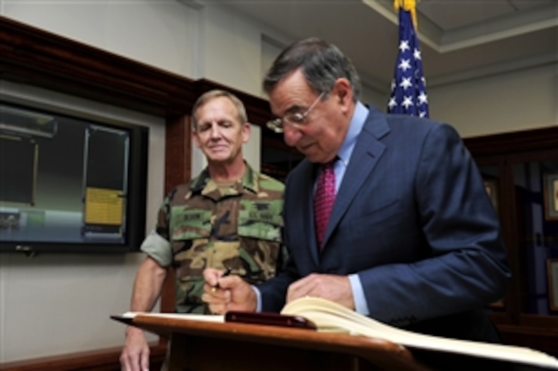 Navy Adm. Eric T. Olson, commander, U.S. Special Operations Command, looks on as Defense Secretary Leon E. Panetta signs a guest book during a visit to USSOCOM headquarters at MacDill Air Force Base, Fla., Aug. 8, 2011. Olson will relinquish command to Adm. William H. McRaven during a change of command ceremony.