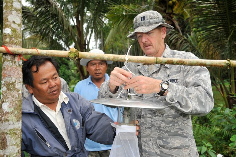 Capt. Wes Walker and Chan Phoum hang a mosquito trap outside a village to examine mosquitoes associated with malaria and dengue in a rural part of Cambodia Aug. 6, 2011, during Operation PACIFIC ANGEL 11-1.  According to the Centers for Disease Control and Prevention, Cambodia had 57,232 reported cases of malaria from 2000 to 2005; cases climbed to 64,595 in 2009. Walker is an entomologist assigned to Kadena Air Base, Japan. Phoum is a local field malaria researcher. (U.S. Air Force photo/Staff Sgt. Christopher Boitz)