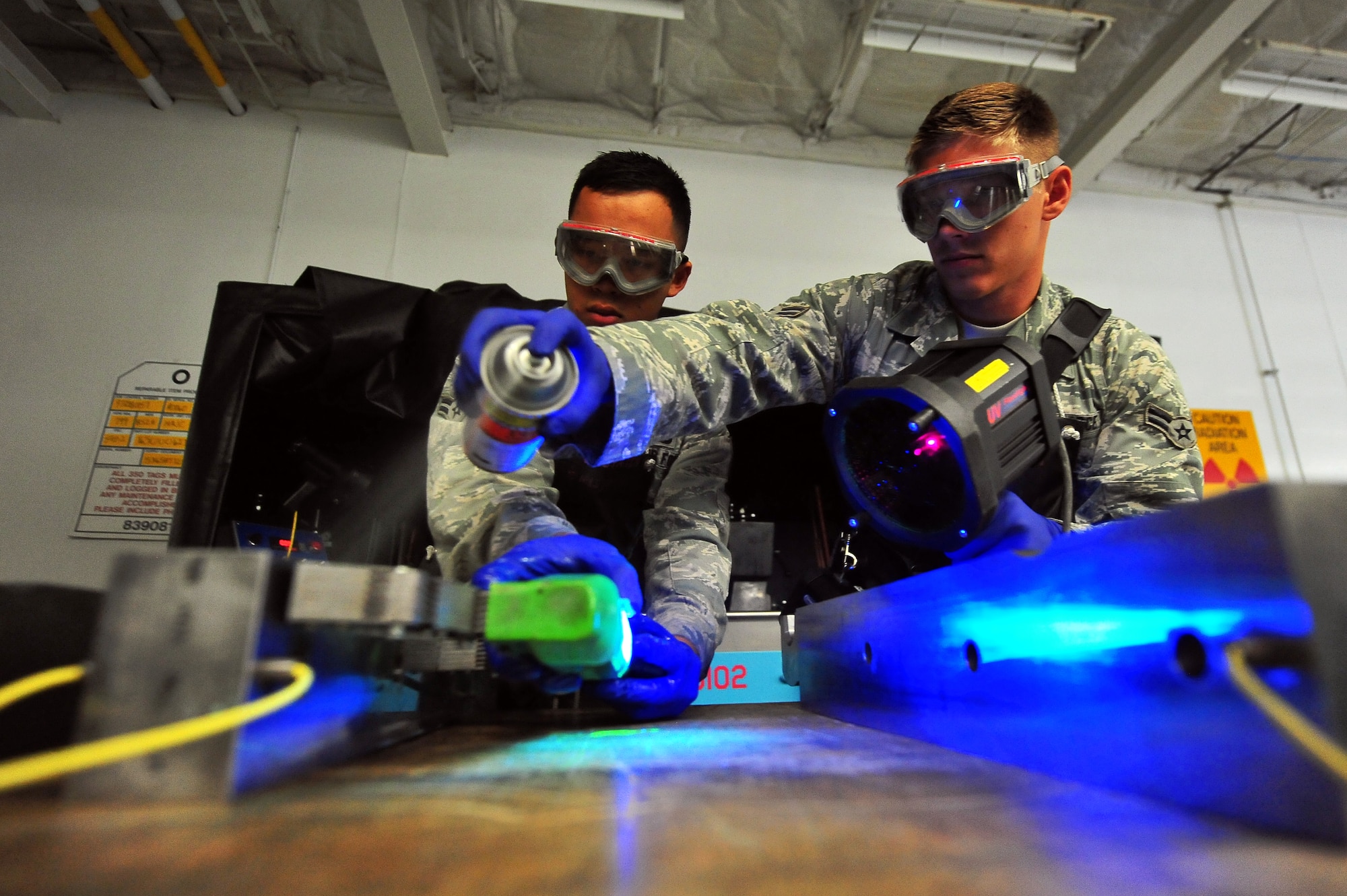 MINOT AIR FORCE BASE, N.D.  – Airman 1st Class Charles Sothikhoun, 5th Maintenance Squadron non-destructive inspection journeyman, and Airman 1st Class Jarred Irick, 5th MXS NDI apprentice, spray down parts of a B-52H Stratofortress and perform a magnetic particle inspection allowing inspectors to track internal cracks and discontinuities within the equipment, here Aug. 8. NDI is the examination of aerospace weapon systems components and support equipment for structural integrity using nondestructive inspection methods and fluid analysis. (U.S. Air Force Photo/ Senior Airman Jesse Lopez)