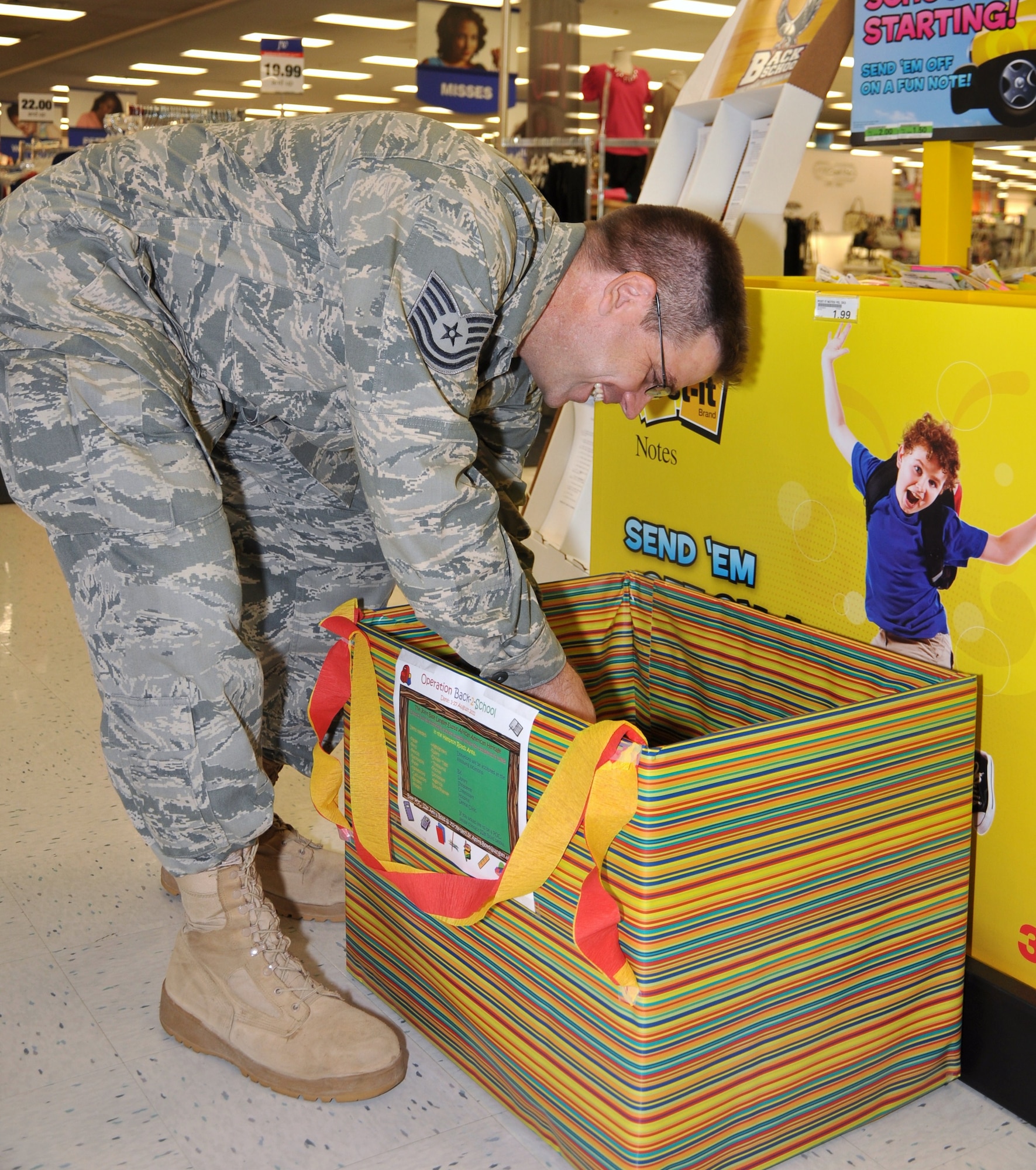 Tech. Sgt. Robert Williams, 633rd Medical Operations Squadron, places pens, pencils and paper into a colorfully decorated donation box in the Exchange store at Langley Air Force Base, Va., Aug. 9, 2011. The donations will benefit the Joint Base Langley-Eustis African-American Heritage Council school supply drive, which provides local area high schools with new school supplies. The drive runs through Aug. 31. (U.S. Air Force photo by Senior Airman Jason J. Brown)