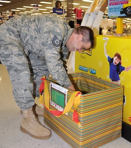 Tech. Sgt. Robert Williams, 633rd Medical Operations Squadron, places pens, pencils and paper into a colorfully decorated donation box in the Exchange store at Langley Air Force Base, Va., Aug. 9, 2011. The donations will benefit the Joint Base Langley-Eustis African-American Heritage Council school supply drive, which provides local area high schools with new school supplies. The drive runs through Aug. 31. (U.S. Air Force photo by Senior Airman Jason J. Brown)