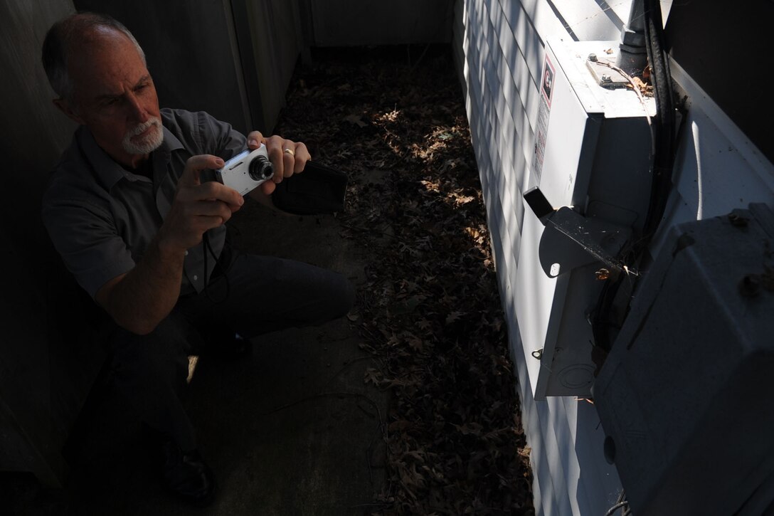 Joseph Novack, 633rd Air Base Wing Safety Office senior safety specialist, takes photos of a safety hazard at Fort Eustis, Va., July 27, 2011. The safety office verifies safe work environments and practices through mishap investigations which aid in preventing similar mishaps. (U.S. Air Force photo by Airman 1st Class Racheal Watson/Released)