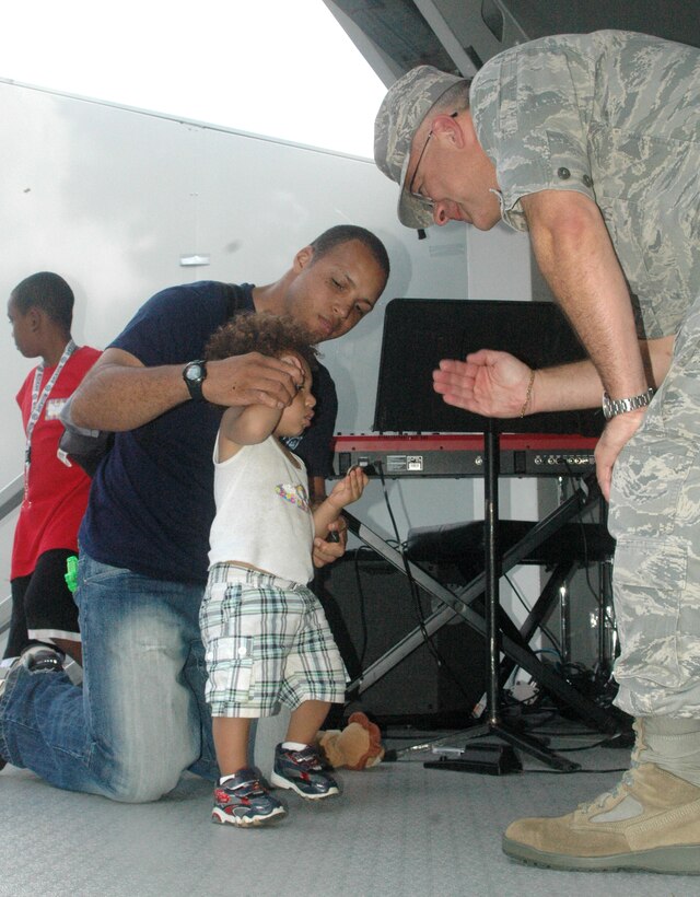 Army Spec. Christopher Smith, with the Pennsylvania Army National Guard, helps his son Christopher Smith Jr. salute Col. Randal L. Bright, 512th Airlift Wing commander, during the wing commanders call Aug. 6 at Eagle's Nest. The one-year-old's mother is Senior Airman Lademicka Smith, 512th Memorial Affairs Squadron. Christopher and 50 other children toured the base as part of the Galaxy Adventure earlier that morning. All the children went on stage to receive a coin from wing leadership. The tour, hosted by the 512th Airman and Family Readiness Center, showed children of reservists what their parents do while they are working for the Air Force Reserve. (U.S. Air Force photo by Capt. Marnee A.C. Losurdo)