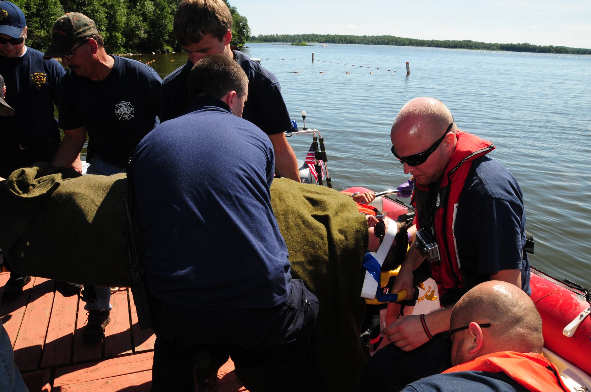 Members of the St. Louis County Rescue Squad and Fredenberg Rescue Squad lift the recovered 148th Fighter Wing pilot safely to shore after transport across Fish Lake July 11, 2011.  Throughout the pilot's ride across the lake, members of the St. Louis County Rescue Squad simulated medical treatment and coordinated with their counterparts back on shore.  (U.S. Air Force photo by Tech. Sgt. Scott G. Herrington)