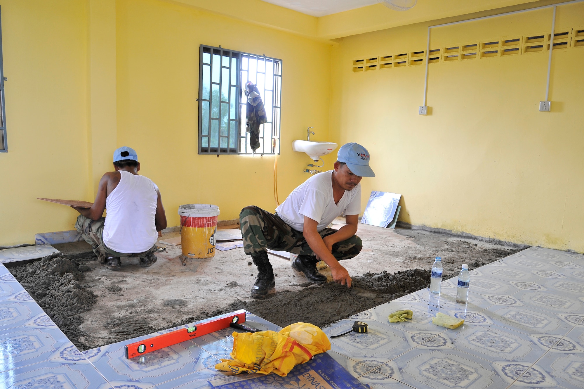 KOH KONG, Cambodia – Royal Cambodian Armed Forces members lay tiles on the inside of clinic here during PACIFIC ANGEL 11-1 Aug. 10, 2011. PA 11-1 partners U.S. and Cambodian military and civilian personnel to provide medical, dental, optometry and engineer programs to local Cambodians as well as airfield operations subject-matter expert exchanges. The clinic received several new improvements including electricity and water storage. (U.S. Air Force photo/Staff Sgt. Christopher Boitz)